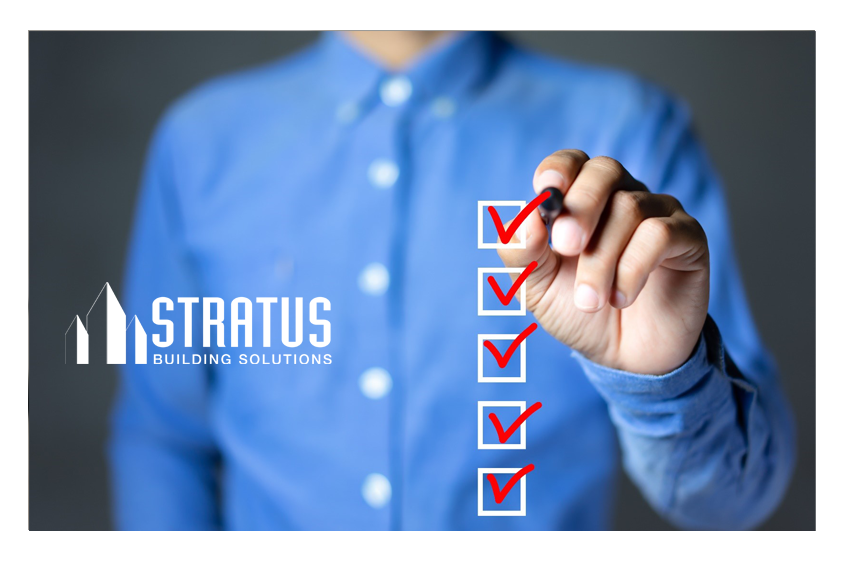 Person wearing a blue button down shirt checking off boxes in the foreground with a red marker. 